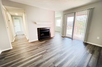 an empty living room with a fireplace and a sliding glass door at Deercross Apartments, Cincinnati, 45236